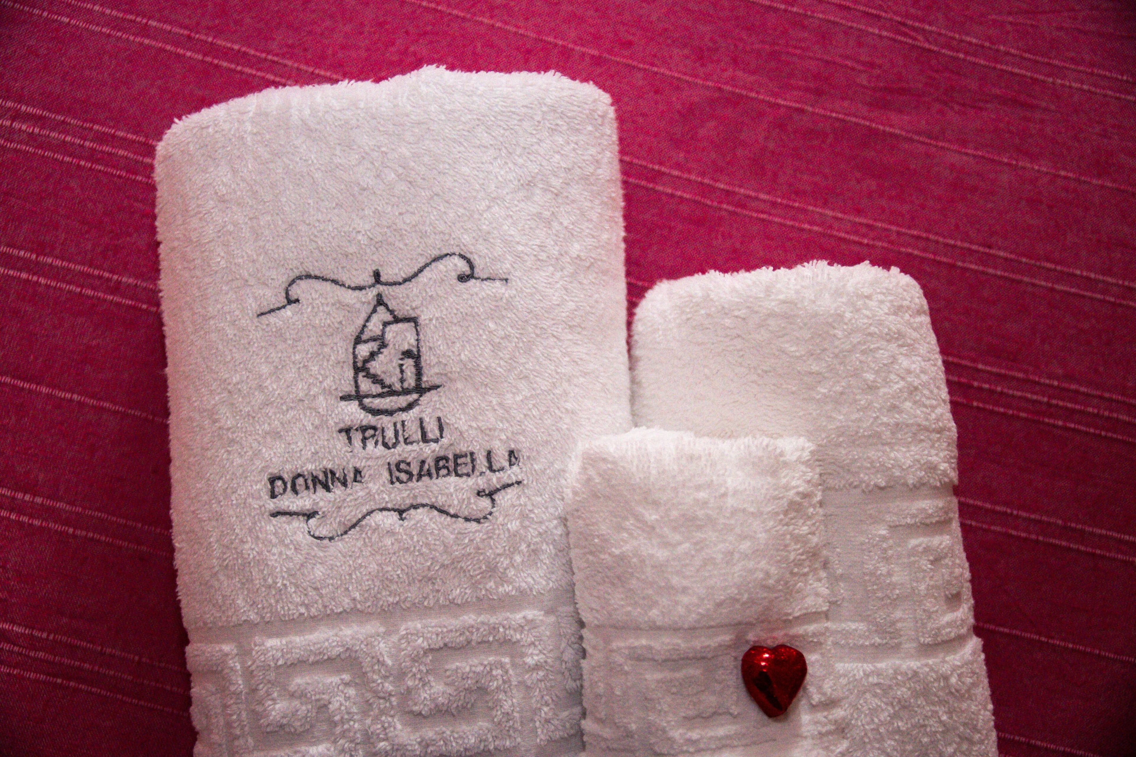 Two white towels with embroidered text and a heart-shaped decoration.