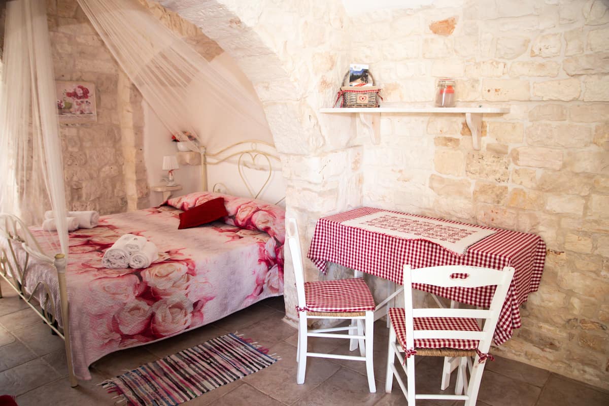 A bedroom with a bed, a table with a checkered tablecloth, and a chair.