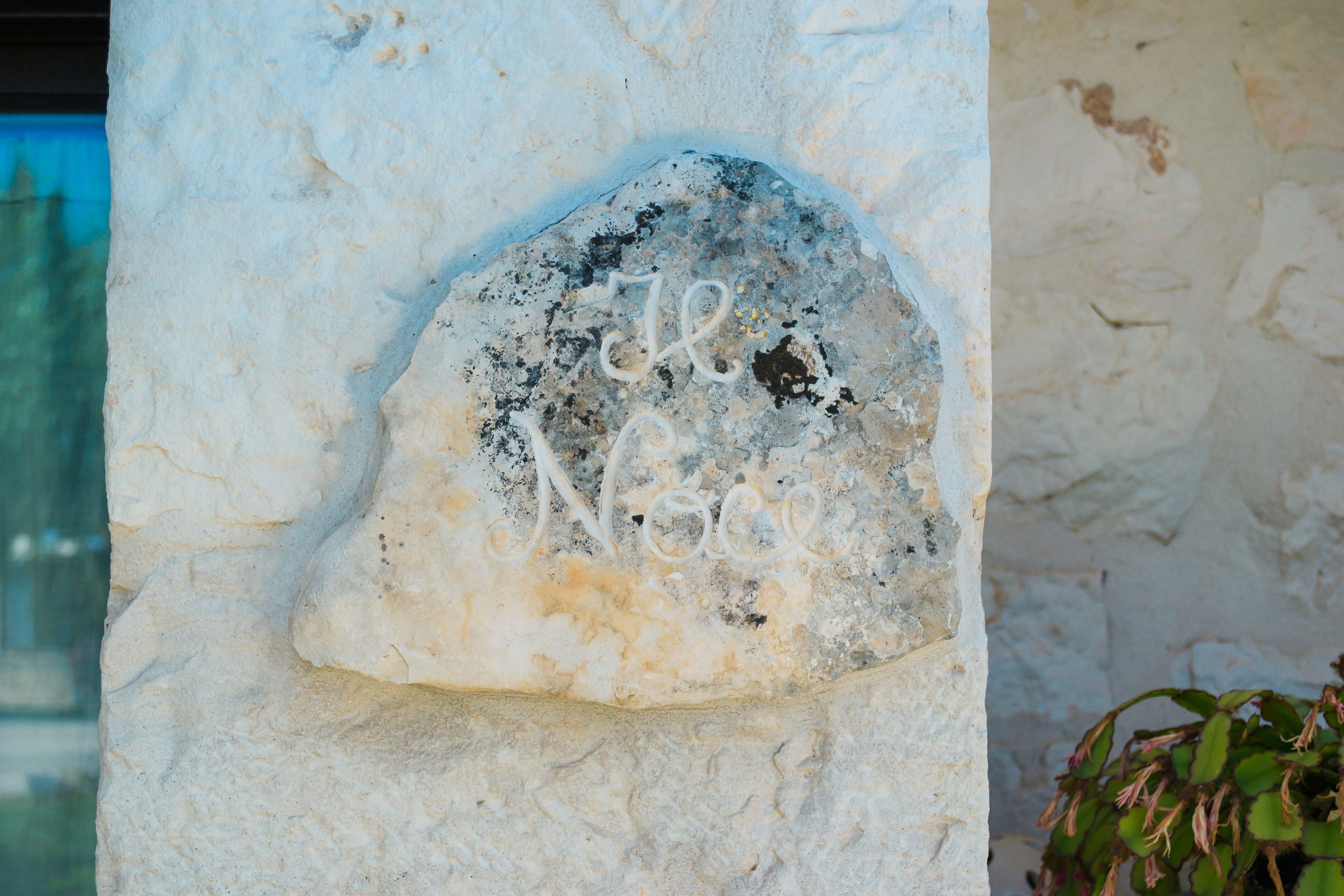 A stone with the inscription "Le Noce" on a building wall.