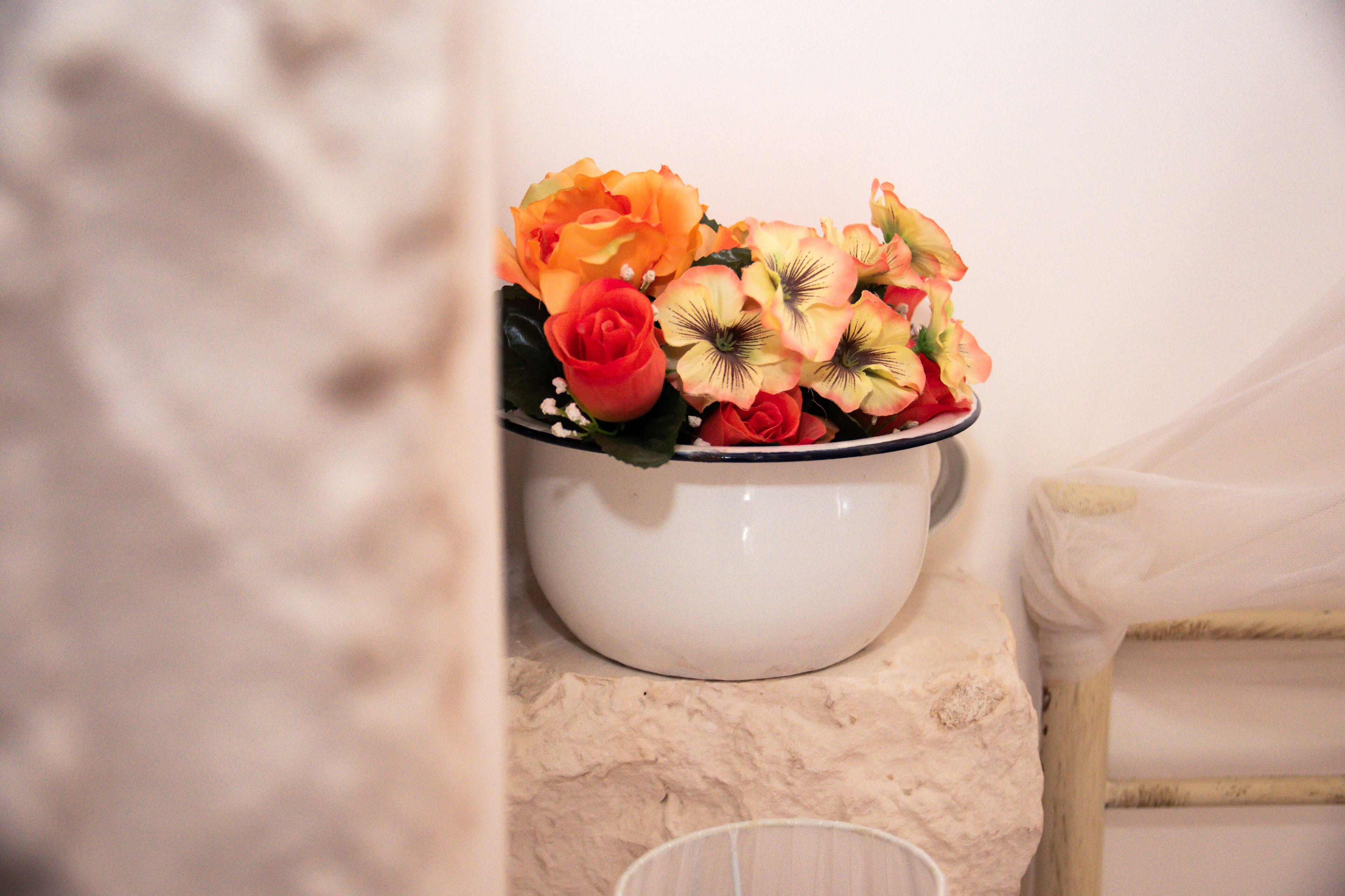 Una ciotola di ceramica bianca con un bouquet di fiori su un piano di marmo.