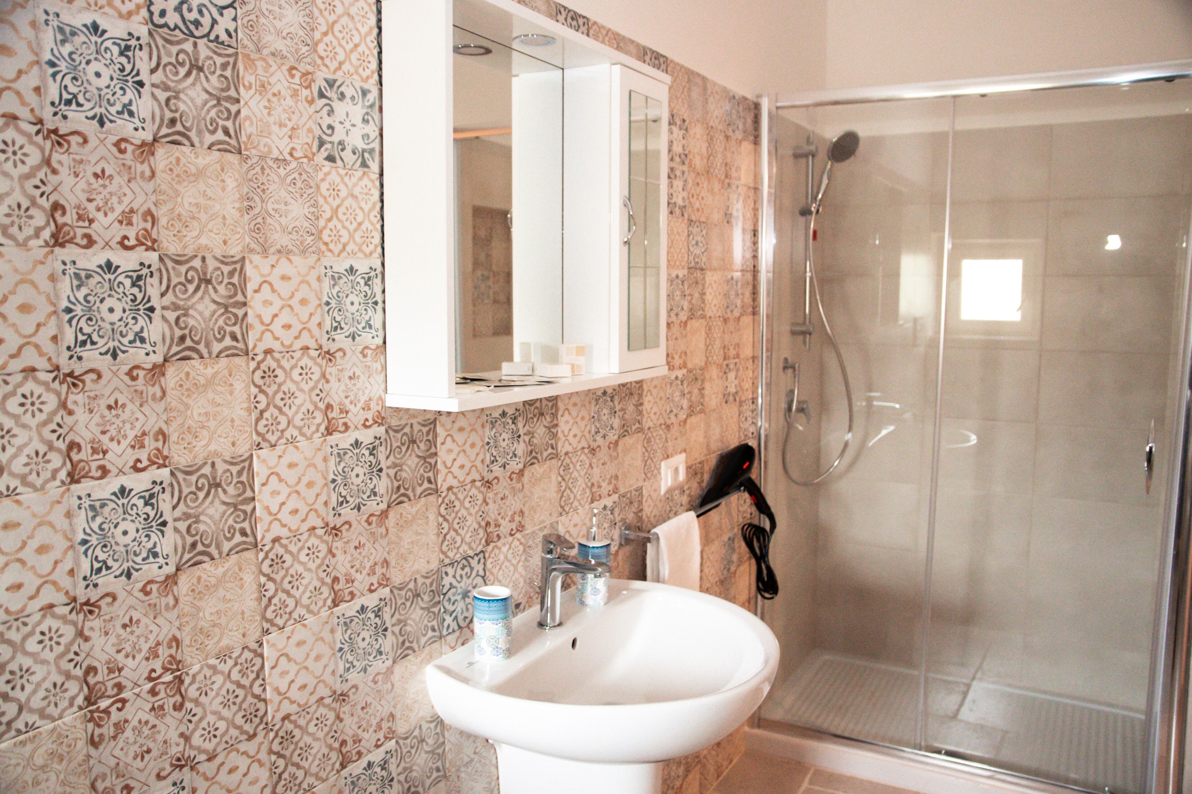 A bathroom with a sink, mirror, and shower.