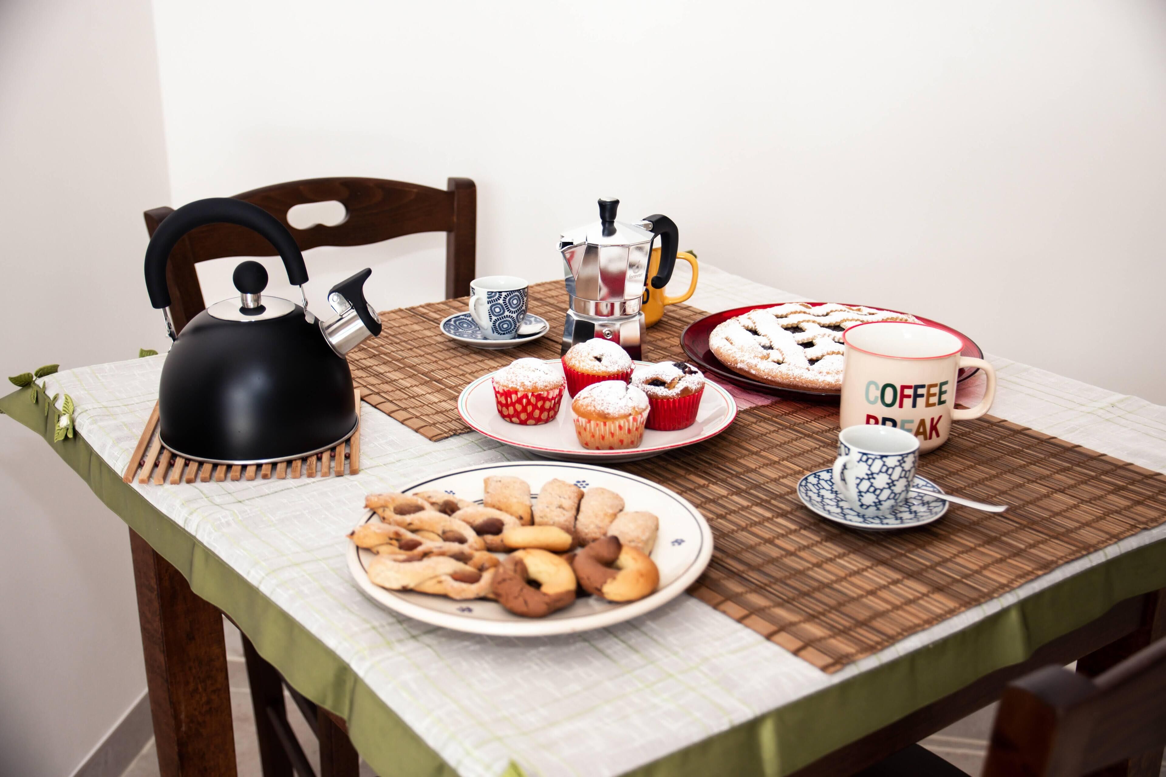 A table set with a black kettle, coffee pot, teapot, and a mug with "COFFEE BREAK" text.
