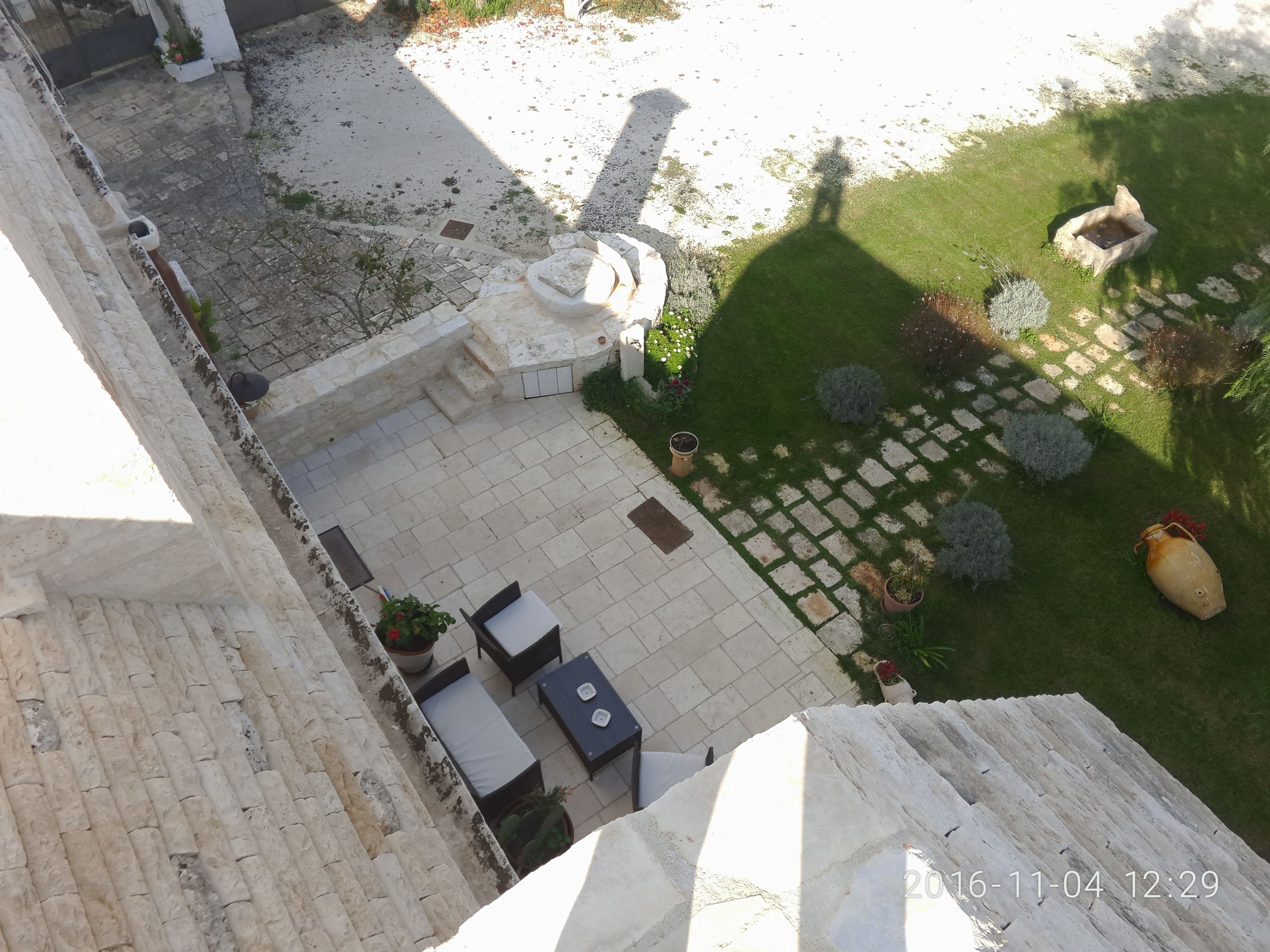 A courtyard with a seating area, stone pathway, and potted plants.