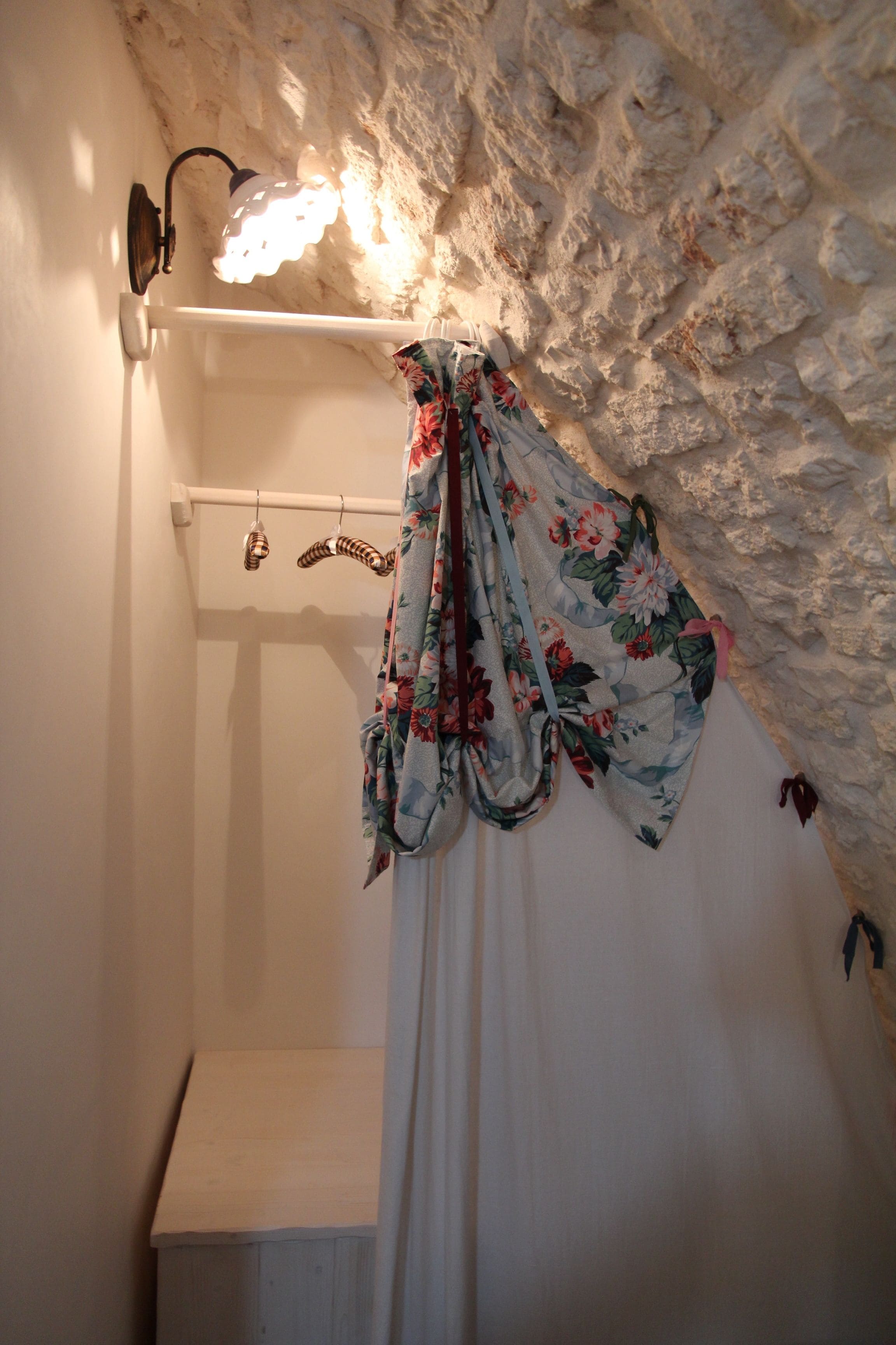 Un baño con una bañera blanca, una cortina de ducha con estampado floral y un aplique de pared.