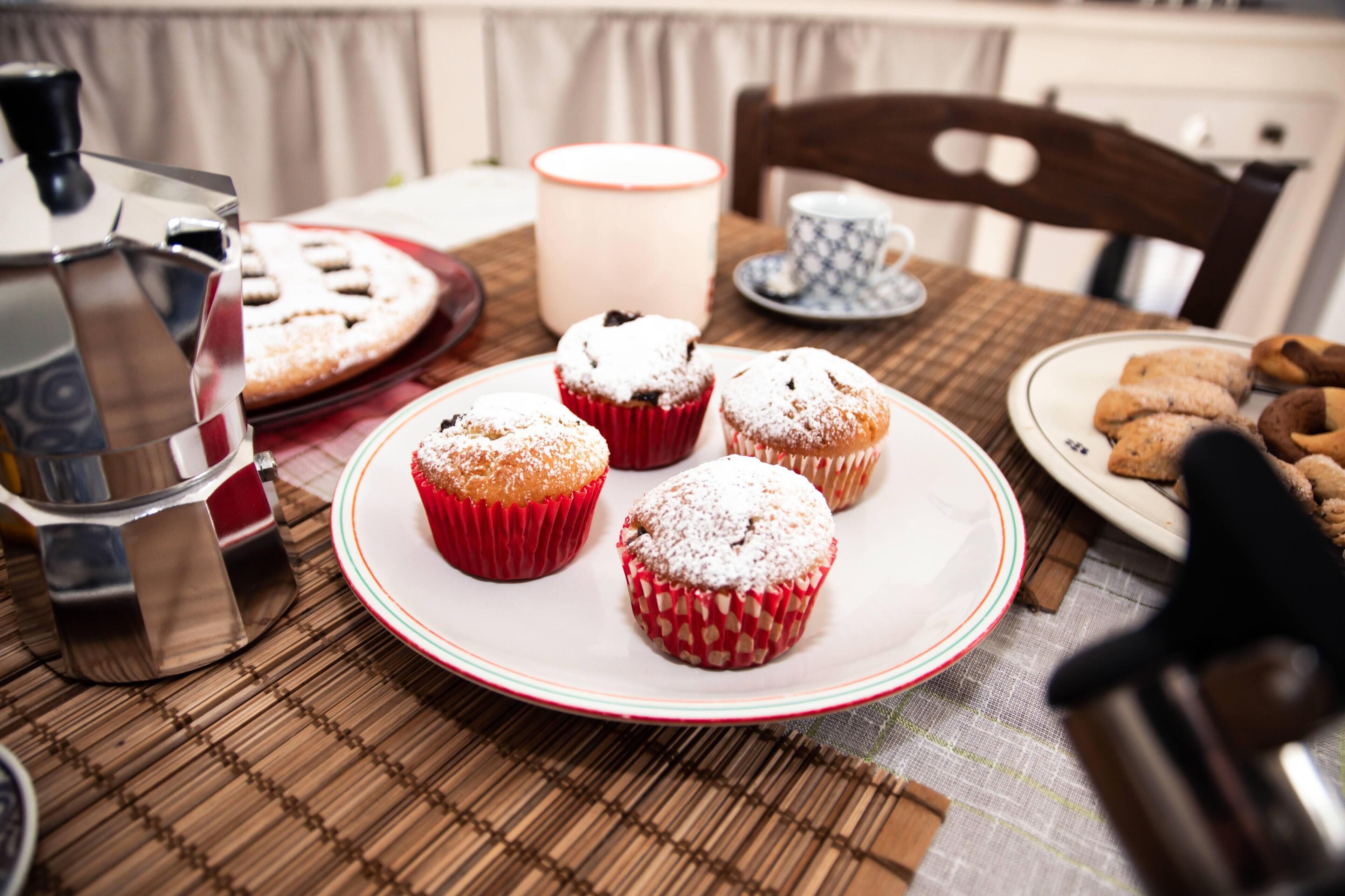 Una mesa con pasteles, una cafetera y una taza.