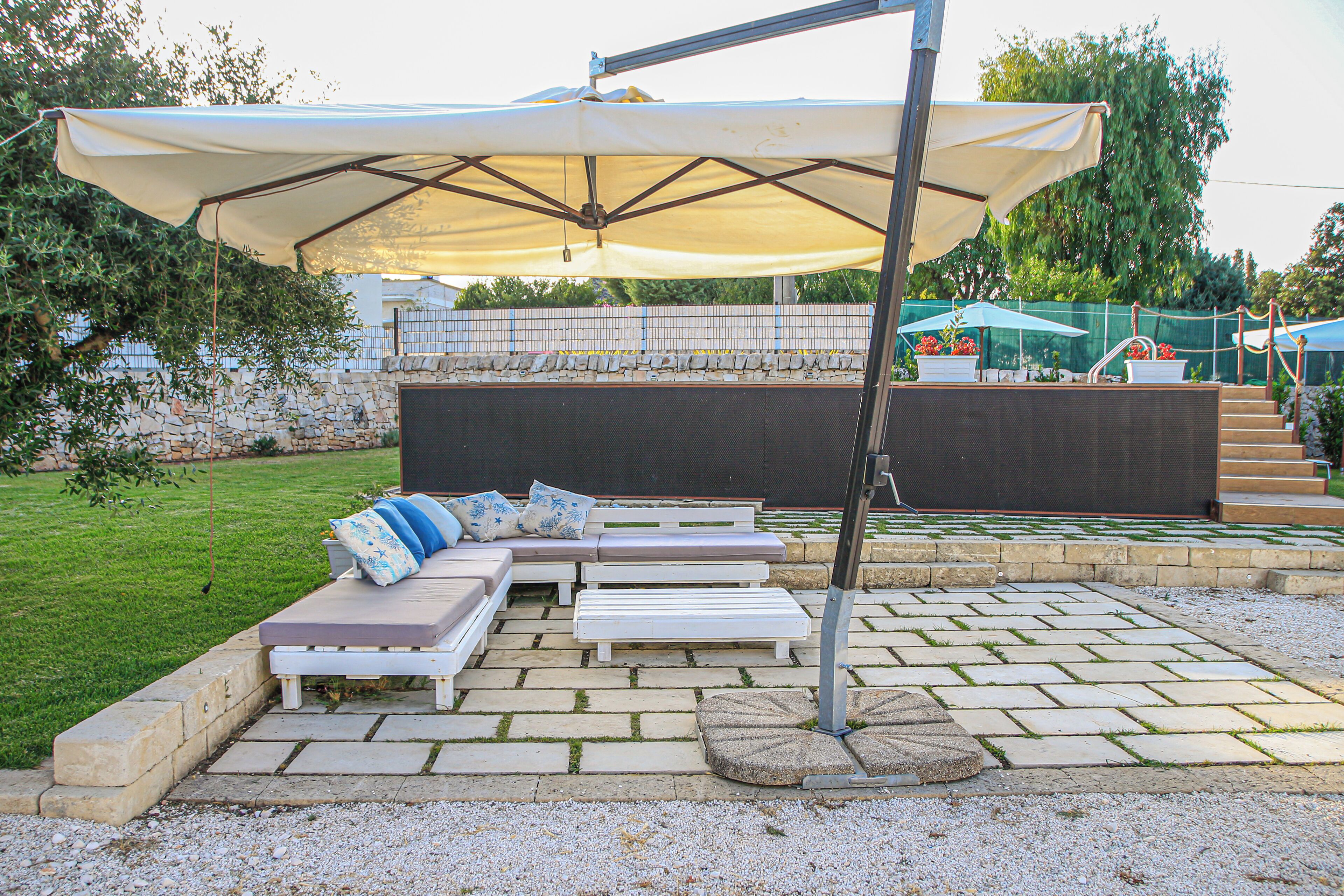 An outdoor seating area with a large umbrella, stone steps, and a stone wall.