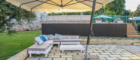 An outdoor seating area with a large umbrella, stone steps, and a stone wall.
