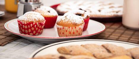 Uma mesa com doces, incluindo muffins e bolachas, em pratos.