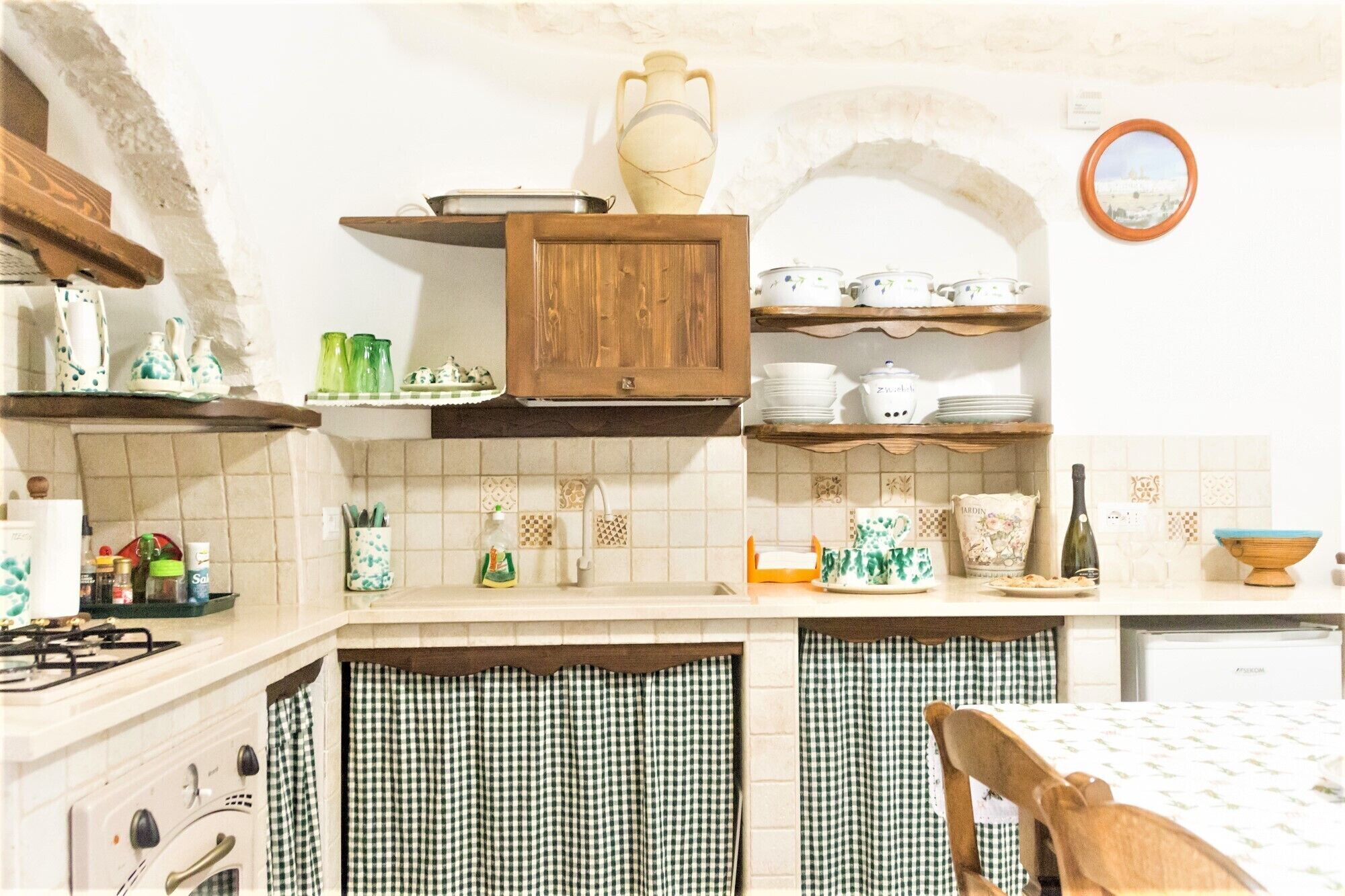 A kitchen with wooden cabinets, a stove, and a table with a checkered tablecloth.