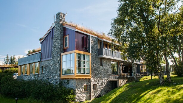 A modern house with stone walls, large windows, and a wooden deck. - Dolmsundet Hotell Hitra (Hitra)