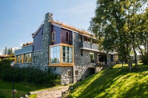 Uma casa moderna com paredes de pedra, grandes janelas e um deck de madeira.