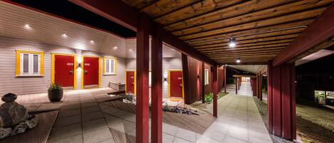 A covered walkway with wooden beams and red doors numbered 222 and 223.