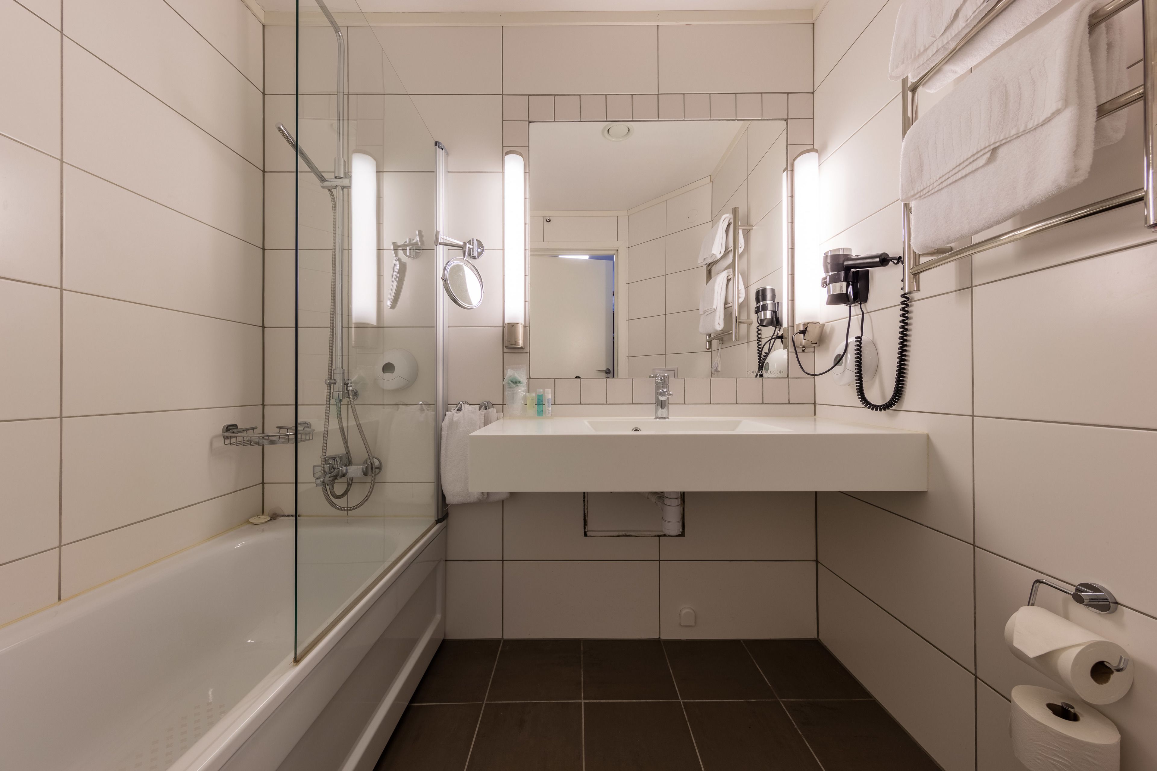 A modern bathroom with a glass-enclosed shower, a white sink, and a mirror above it.