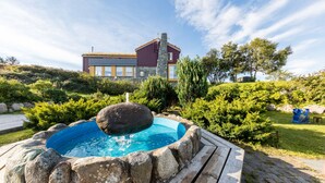 A swimming pool with a stone border, surrounded by a wooden deck. - Dolmsundet Hotell Hitra (Hitra)