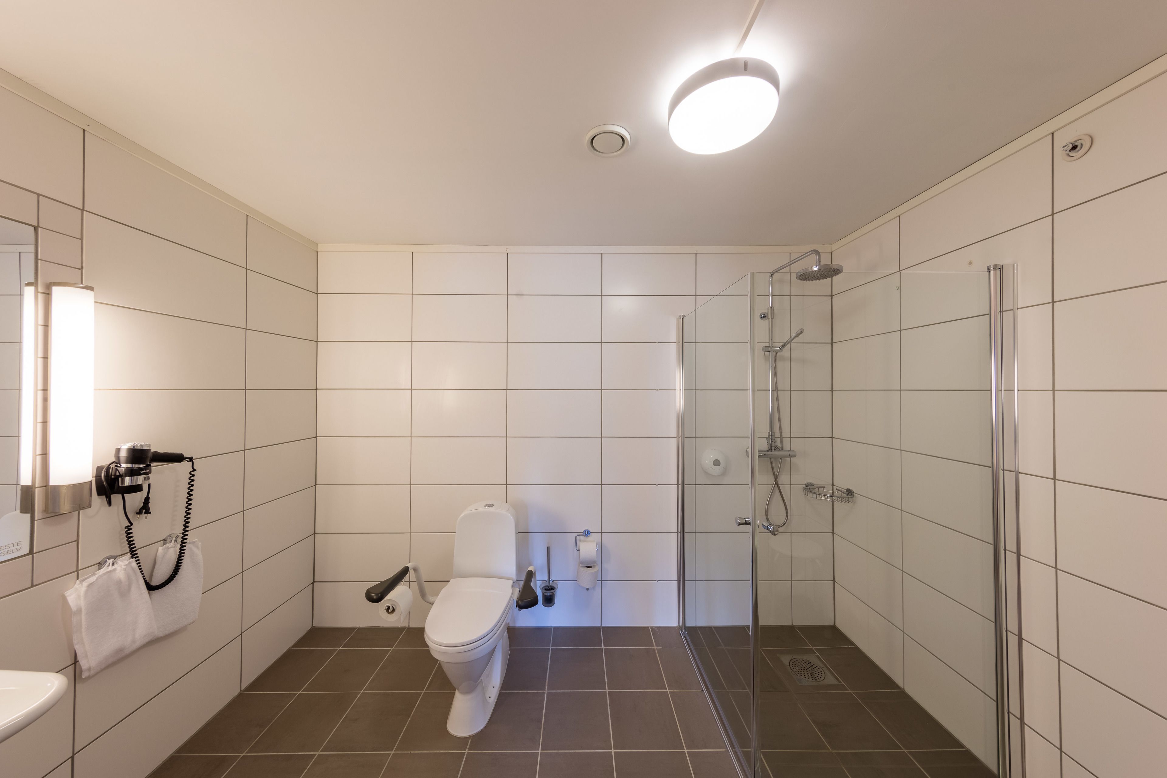 Un baño moderno con inodoro, bidé y cabina de ducha con mampara de vidrio.