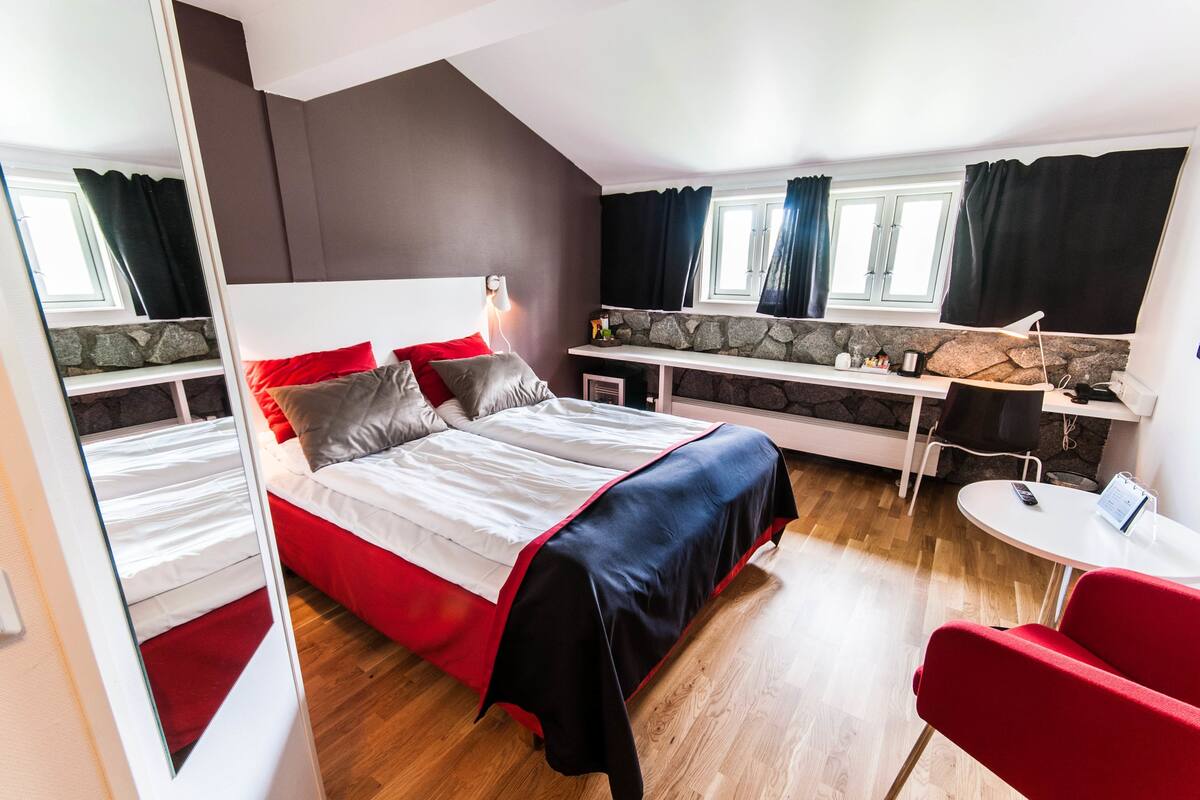 Ein Schlafzimmer mit Bett, Schreibtisch, Stuhl und Fenster.