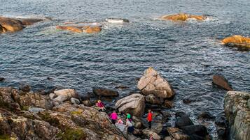 A rocky coastal area with people walking on the rocks and a wooden walkway.