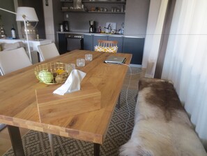 A wooden dining table with a laptop, a bowl, and glasses. A fur-covered bench is in the foreground. - Abnoba Mons Design Apartment (Lenzkirch)