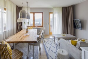 Ein modernes Hotelzimmer mit einem Holztisch, einem grauen Sofa und einem an der Wand befestigten Fernseher.