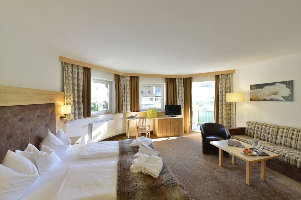 Une chambre d’hôtel comprenant un lit, un bureau, une chaise, un canapé et un téléviseur.