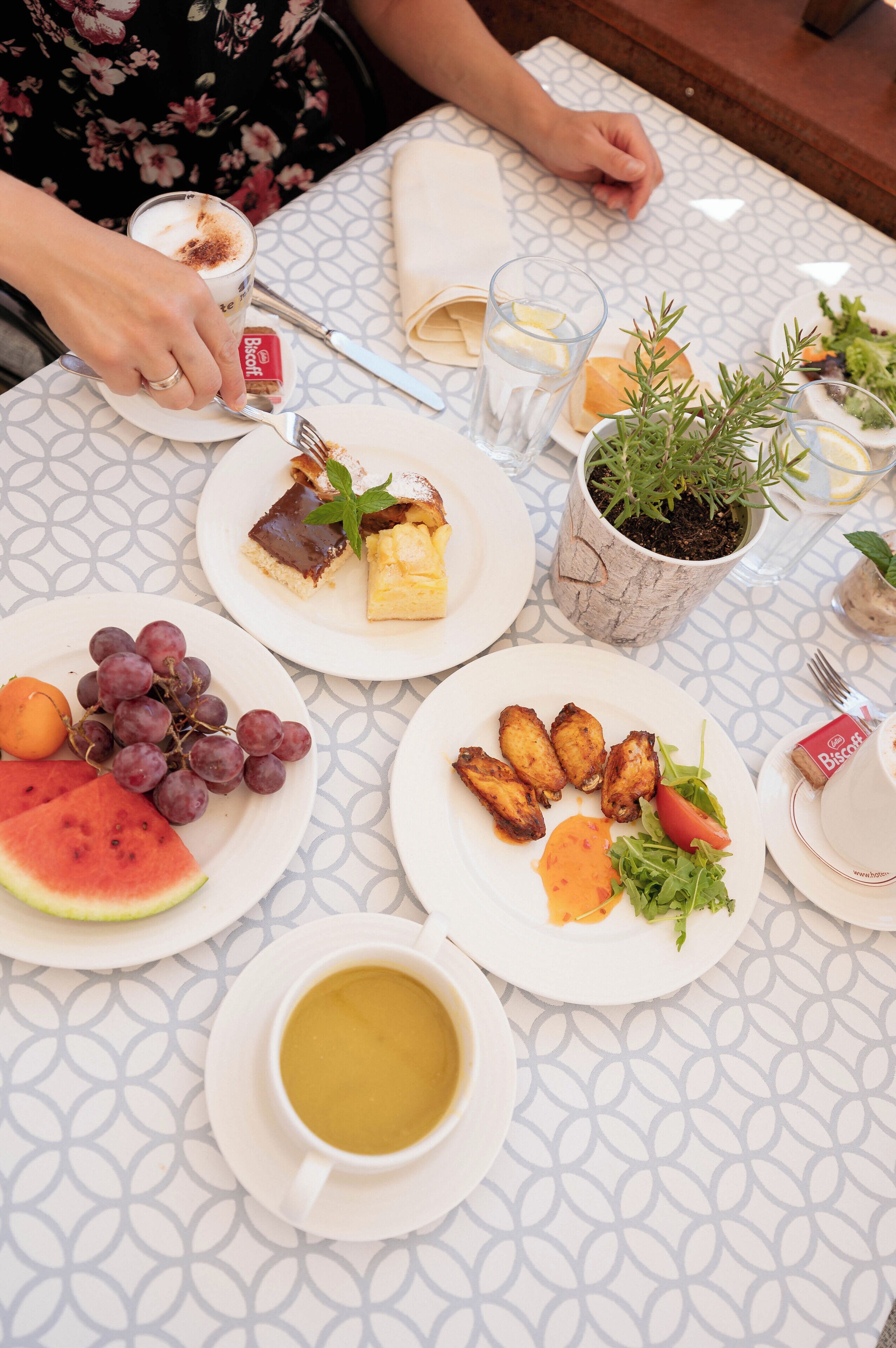 Una mesa dispuesta con platos de comida, incluyendo uvas, sandía y una taza de café.