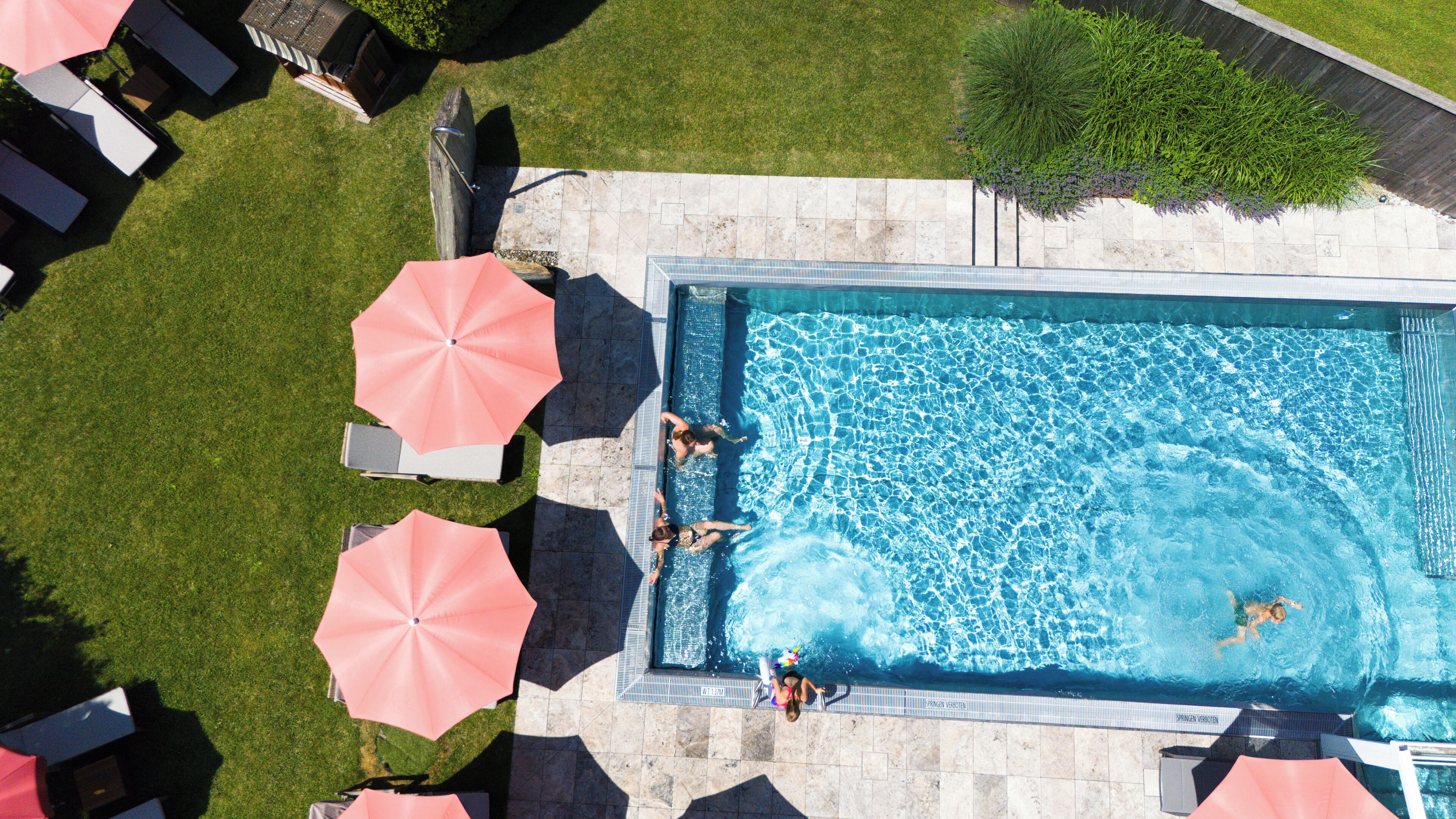 Una piscina techada, una piscina al aire libre, sombrillas