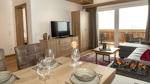 Een moderne woonkamer met een eethoek, een flatscreentelevisie en een open haard.