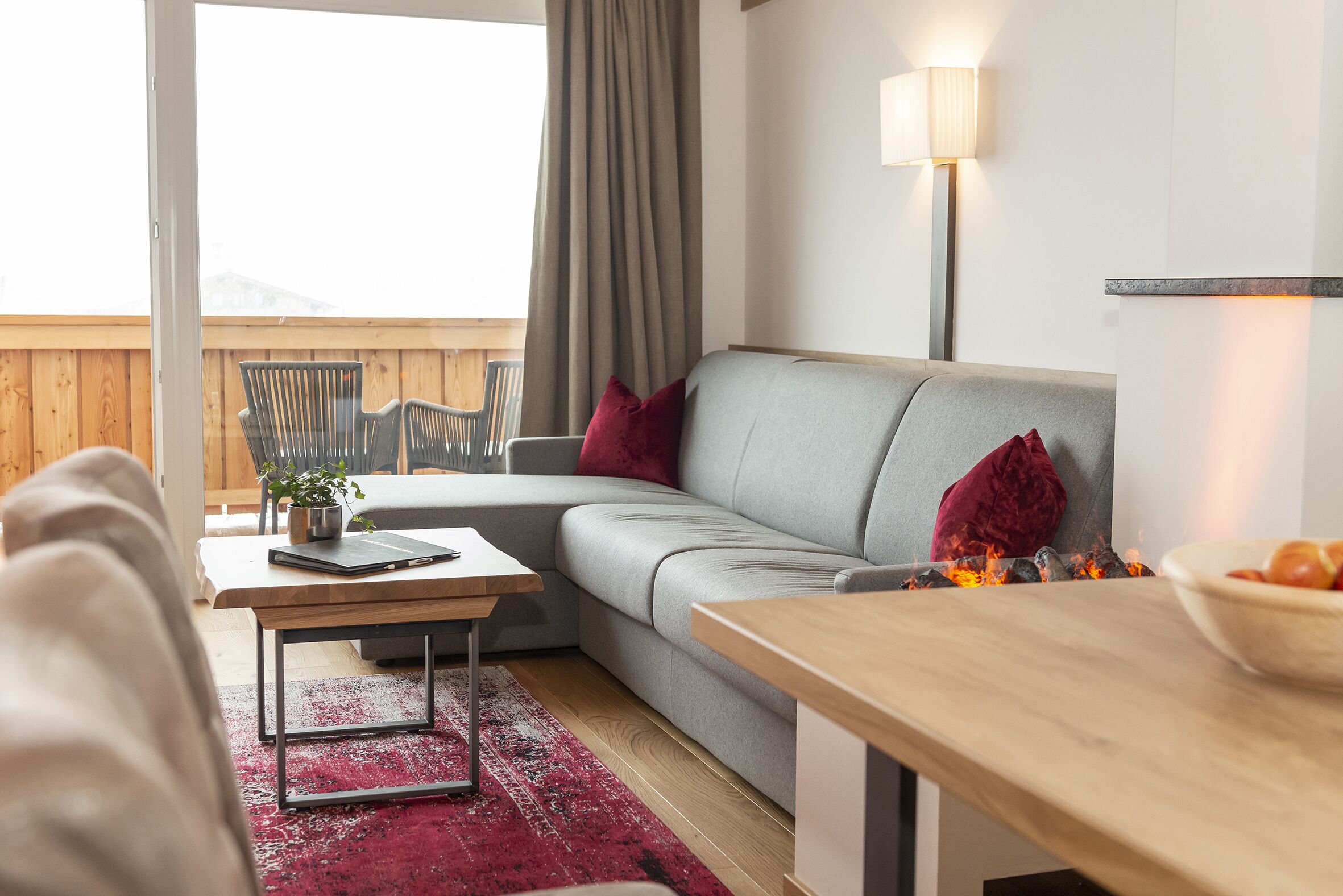 Una sala de estar moderna con un sofá gris, una mesa de centro de madera y una alfombra roja.