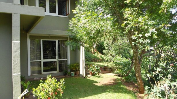 A two-story house with a front yard, a large tree, and a small garden area. - Hanthana Breeze Home Stay (Kandy)