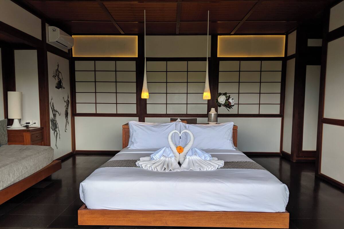 A traditional Japanese-style bedroom with a large bed, wooden headboard, and a decorative swan centerpiece.