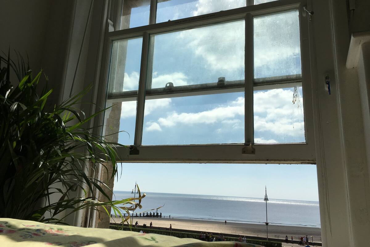 A room with a large window overlooking a beach.