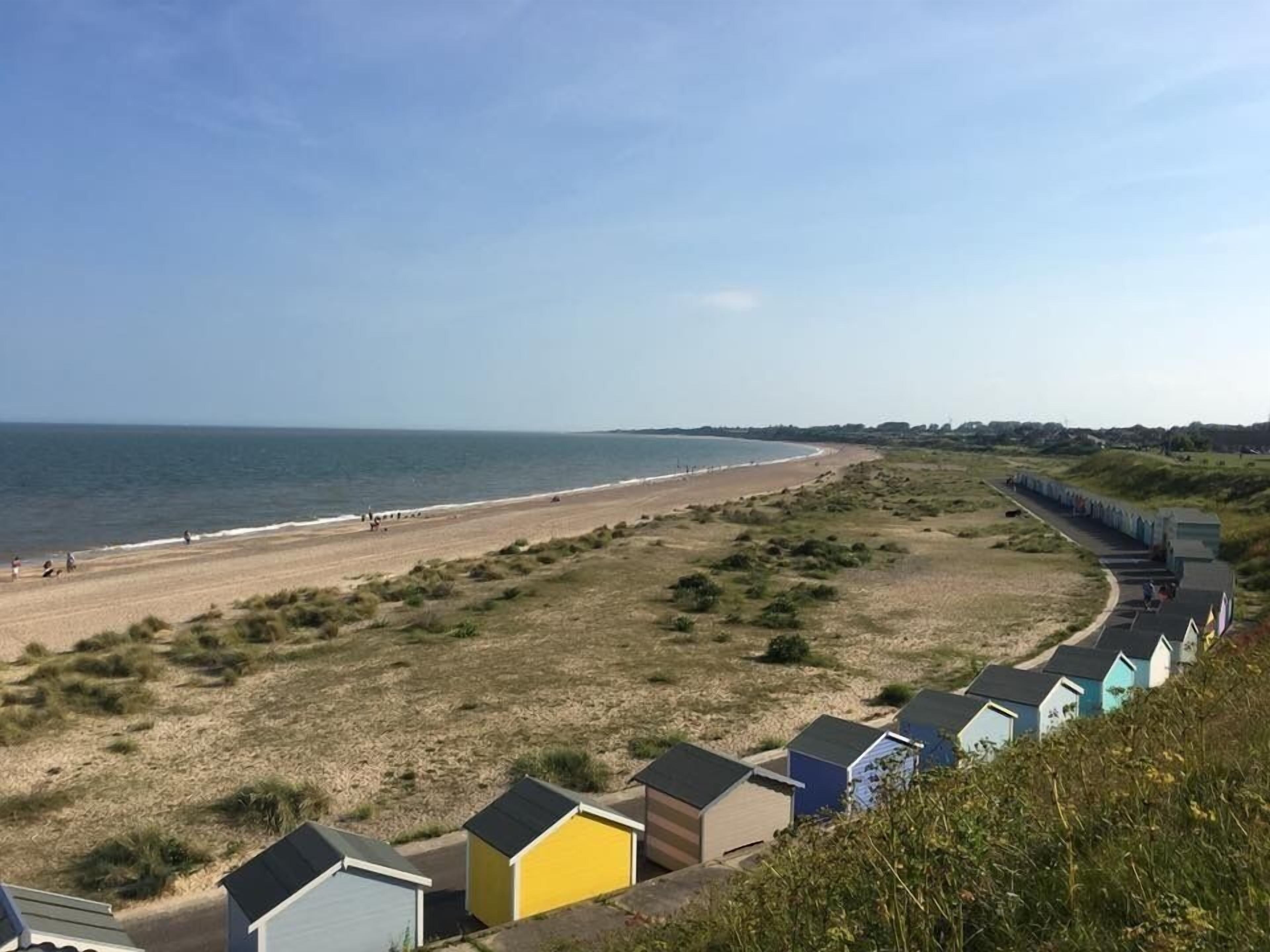 A beach with a row of colorful beach huts along the shore.