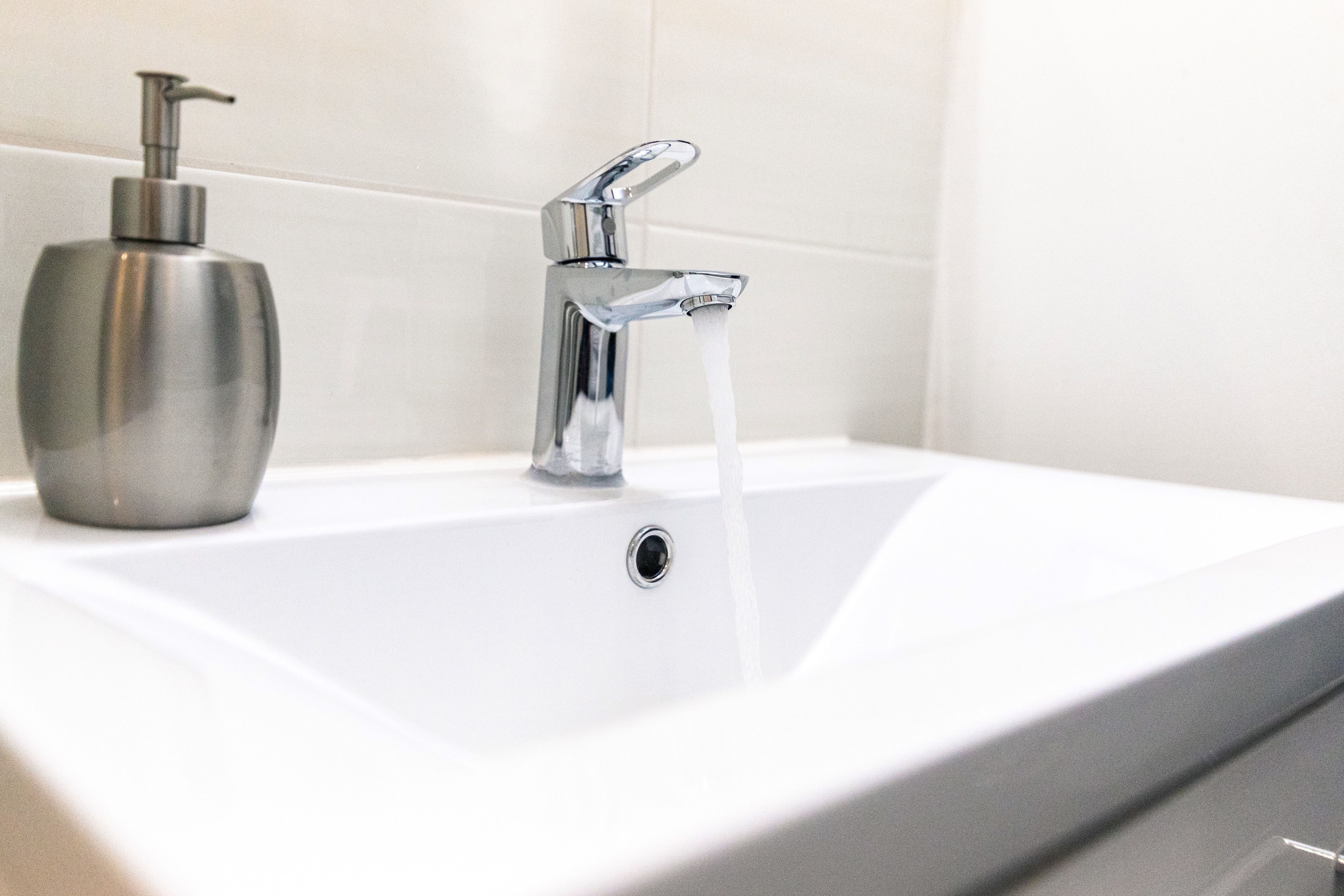 A bathroom sink with a chrome faucet and a soap dispenser.