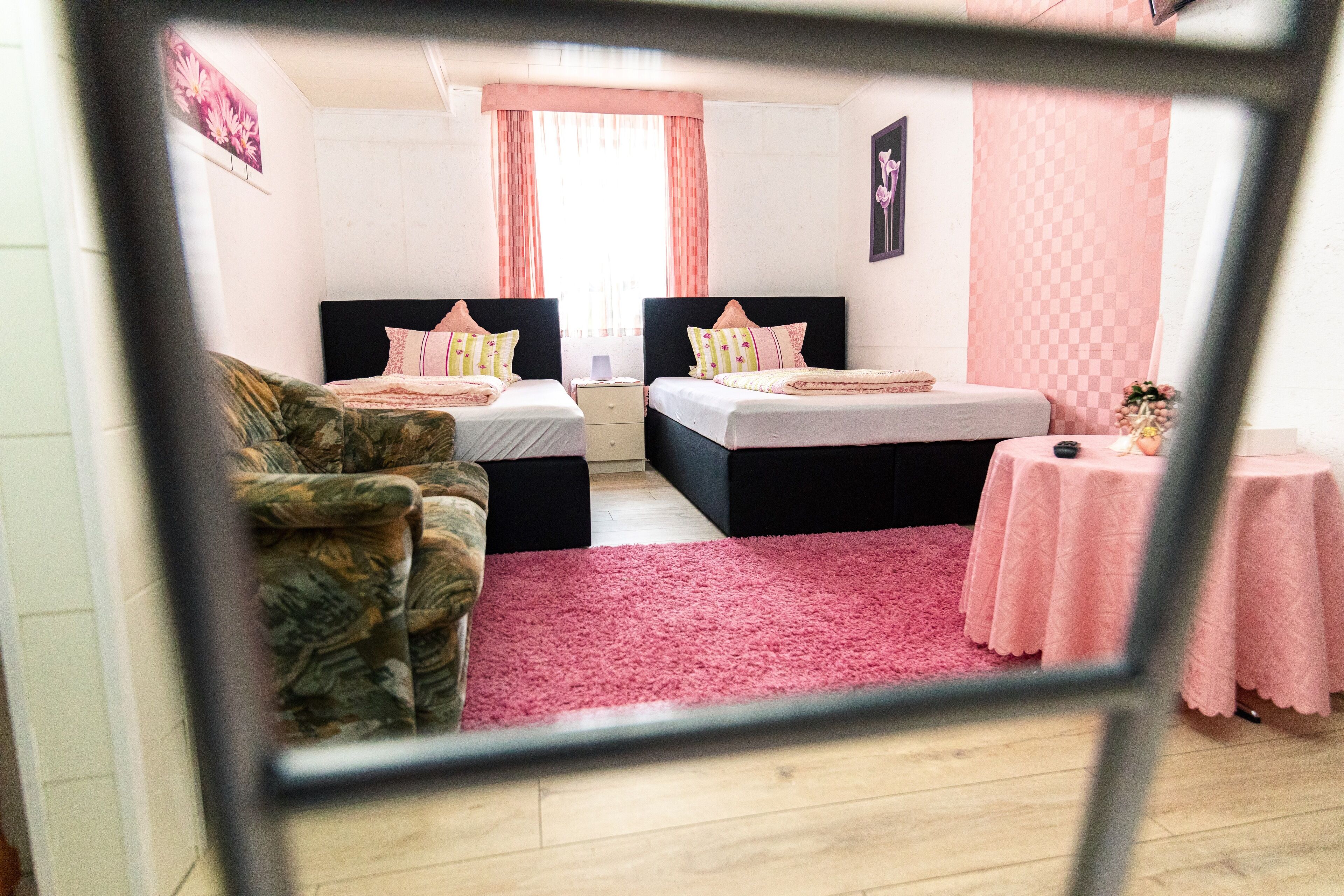 A bedroom with two beds, a sofa, a small table, and a pink rug.