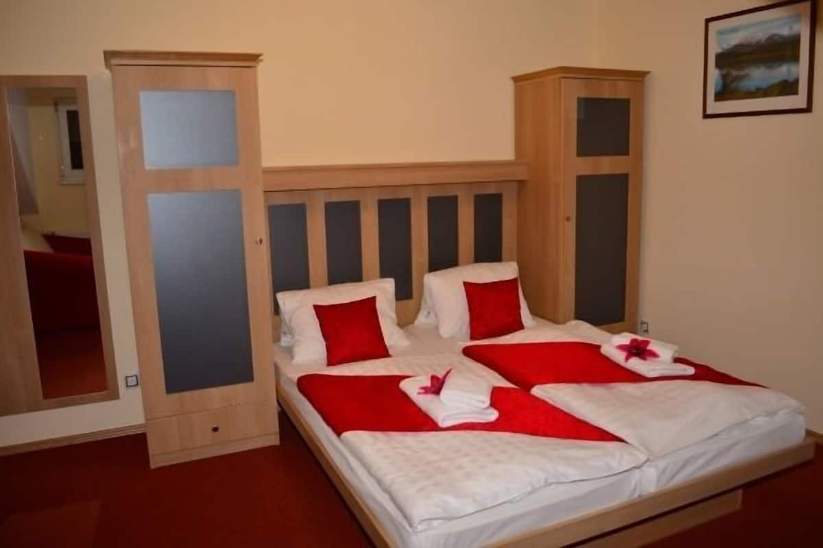 A double bed with red and white bedding, a wooden headboard, and a mirror cabinet.