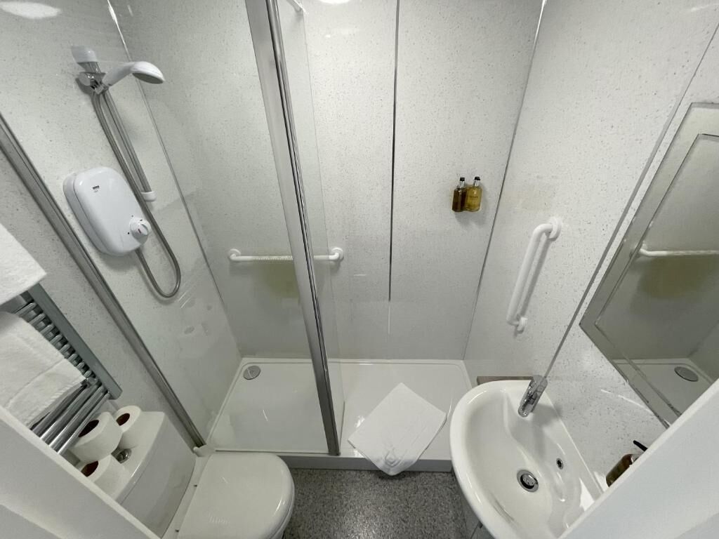 Un bagno moderno e piccolo con box doccia in vetro, un water e un lavandino.