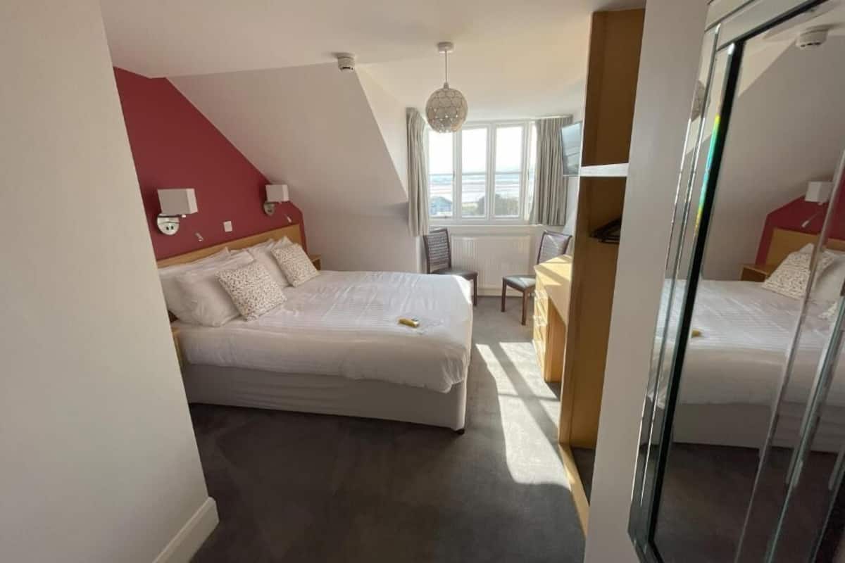 A bedroom with a bed, bedside tables, a chair, a radiator, and a window.