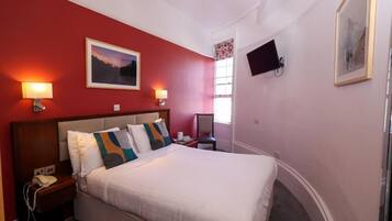 Een hotelkamer met een bed, nachtlampjes, een televisie en een raam.