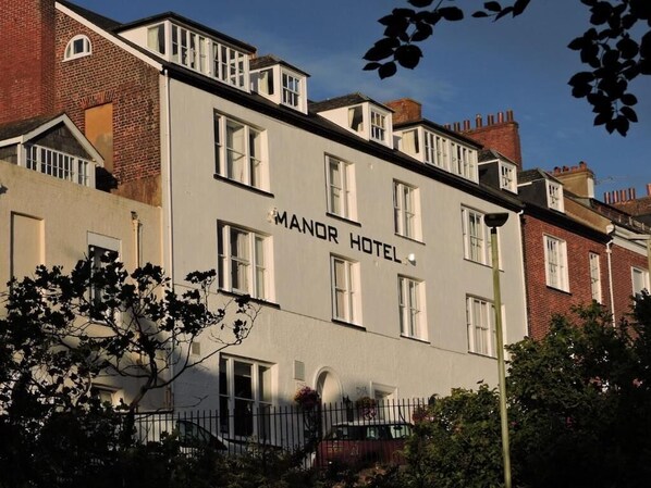 A two-story building with the sign 'MANOR HOTEL' on the facade.