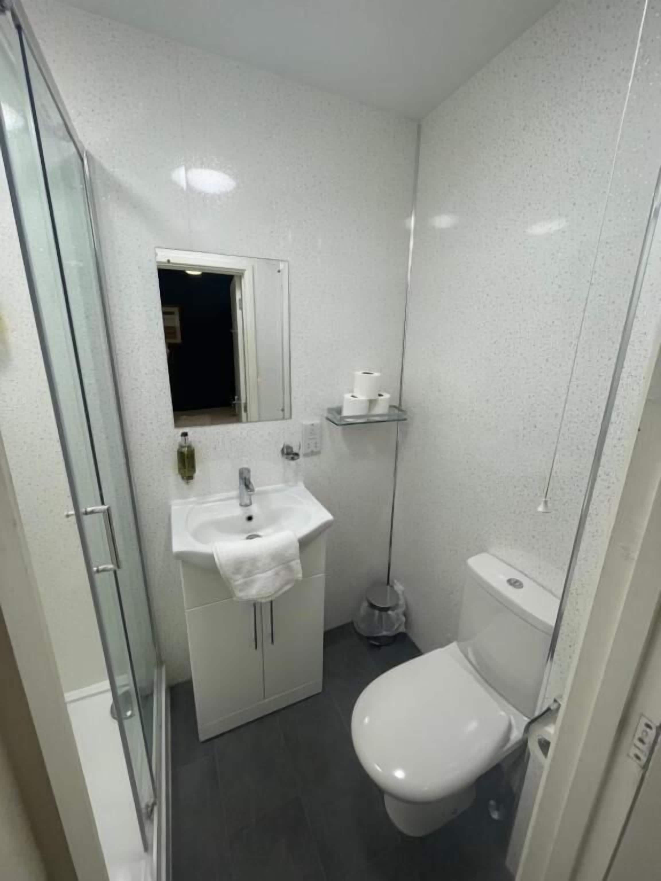 Ein kleines Badezimmer mit Waschbecken, Spiegel und Toilette in Weiß.