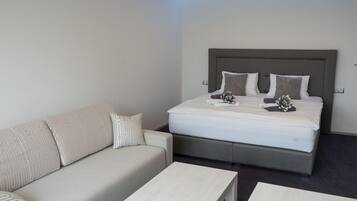 Een hotelkamer met een bed, een slaapbank en twee kleine tafels.