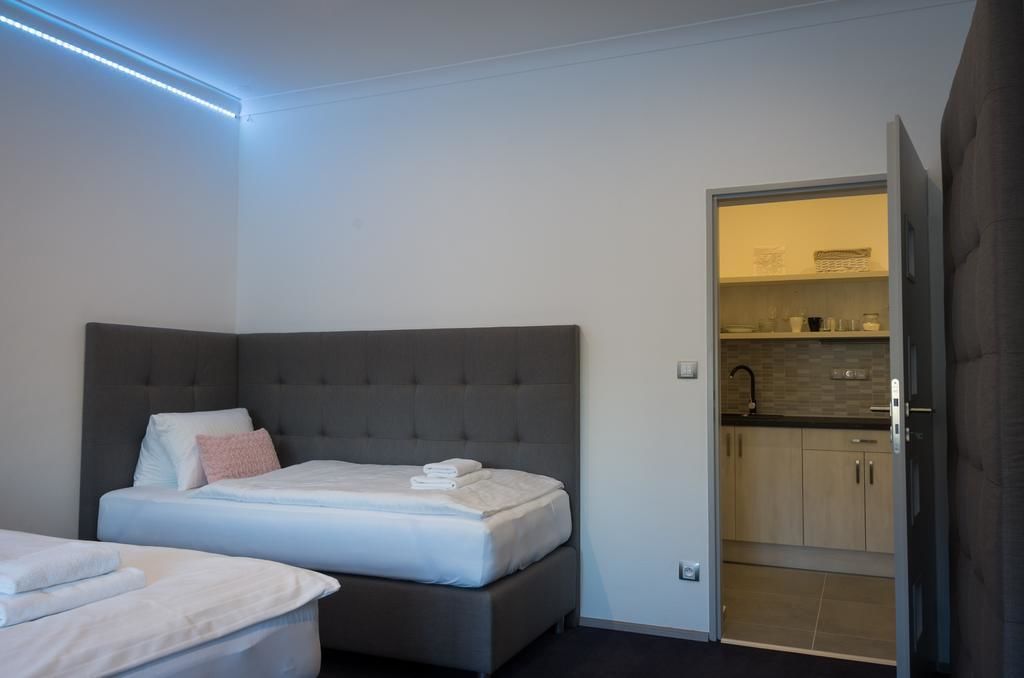 A bedroom with a large bed, a smaller bed, and a kitchenette area.