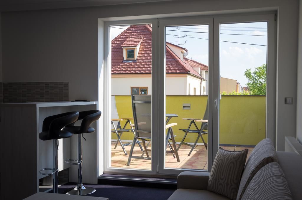 Un salon moderne avec un canapé, un coin repas avec des chaises et un espace cuisine avec un tabouret de bar.