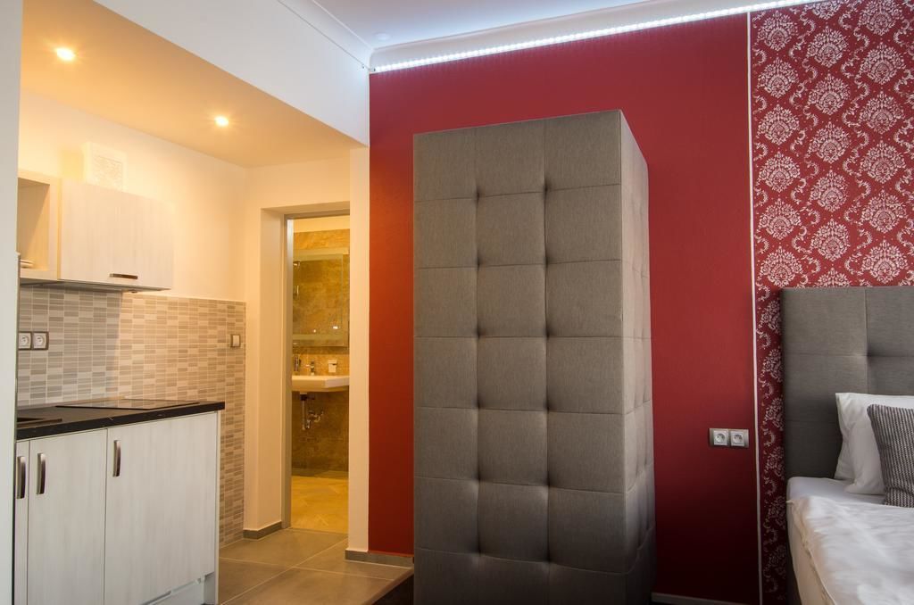 Una habitación de hotel moderna con un cabecero gris con capitoné, una pared de acento roja y un papel pintado estampado.