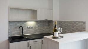 A modern kitchen with a black sink, white cabinets, and a tiled backsplash. - Villa Kiwi (Mikulov)