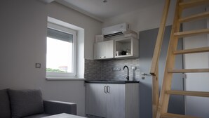 A compact kitchen with a built-in stove, a window, and a wooden ladder. - Villa Kiwi (Mikulov)
