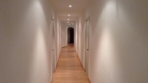 Un largo pasillo estrecho con suelo de madera y paredes blancas.