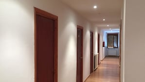 Un pasillo largo y estrecho con piso de madera y paredes blancas.
