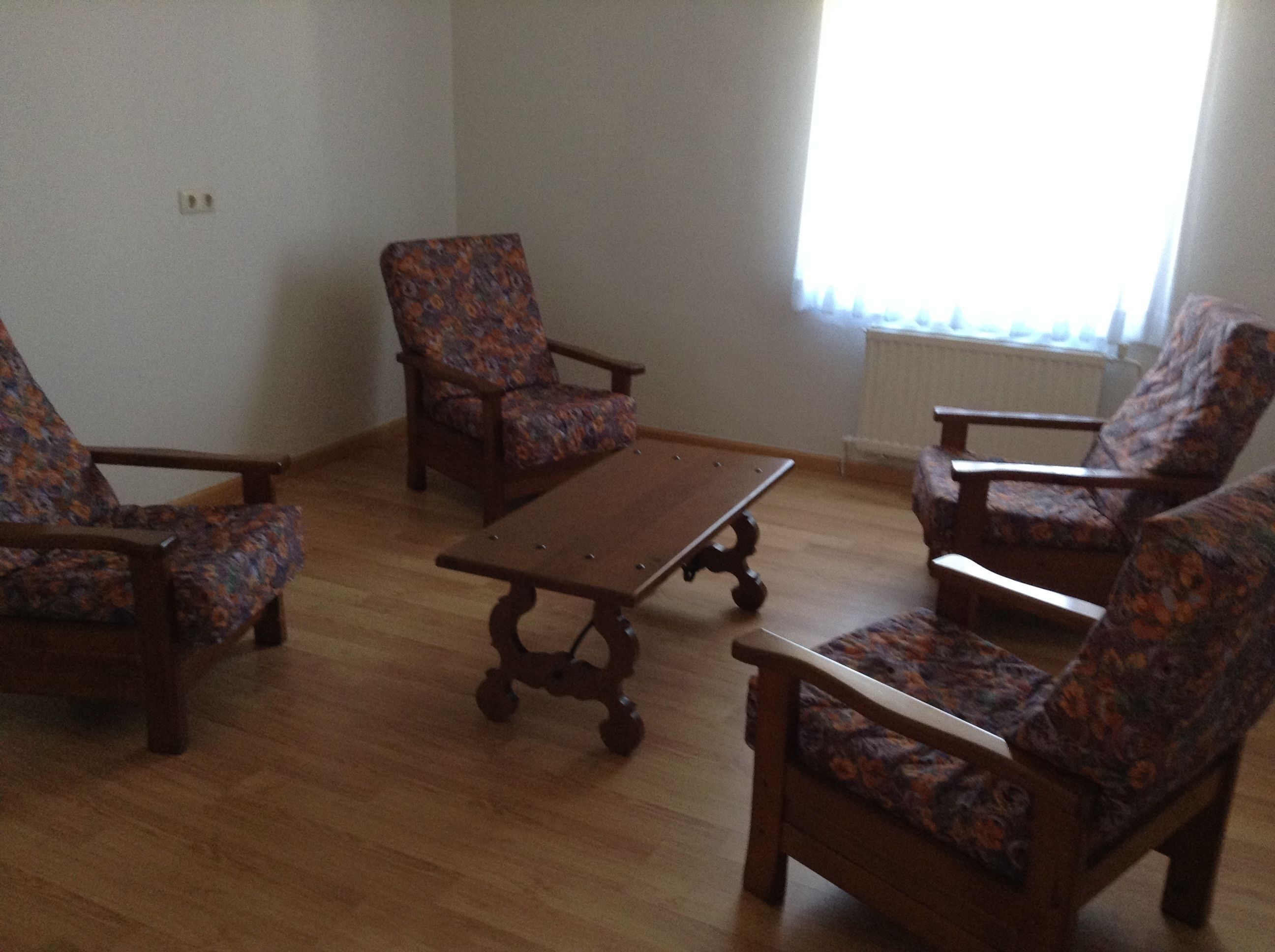 Quarto com piso de madeira, mesa de bilhar e poltronas com padrão floral.
