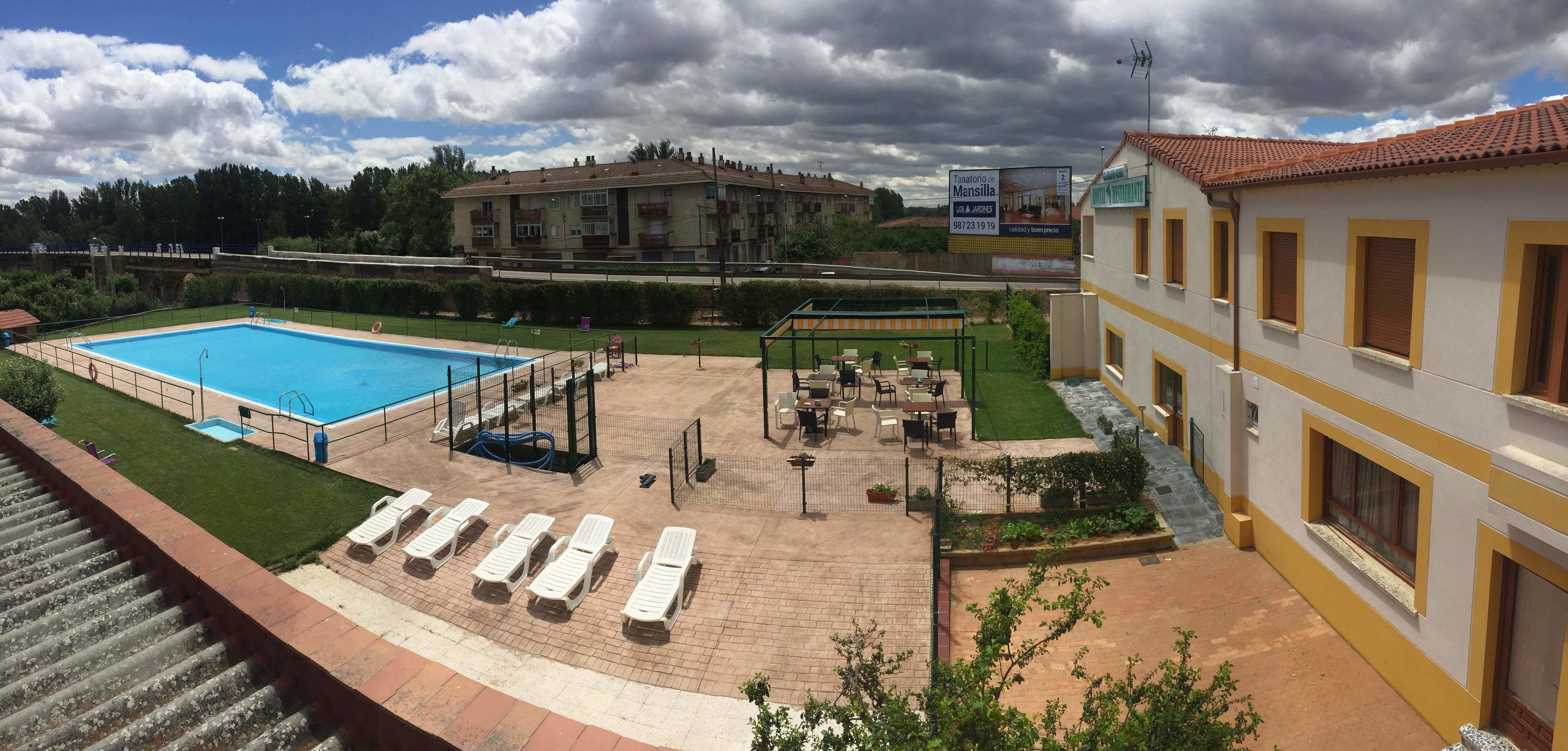 A hotel with a swimming pool, outdoor seating, and a covered patio area.